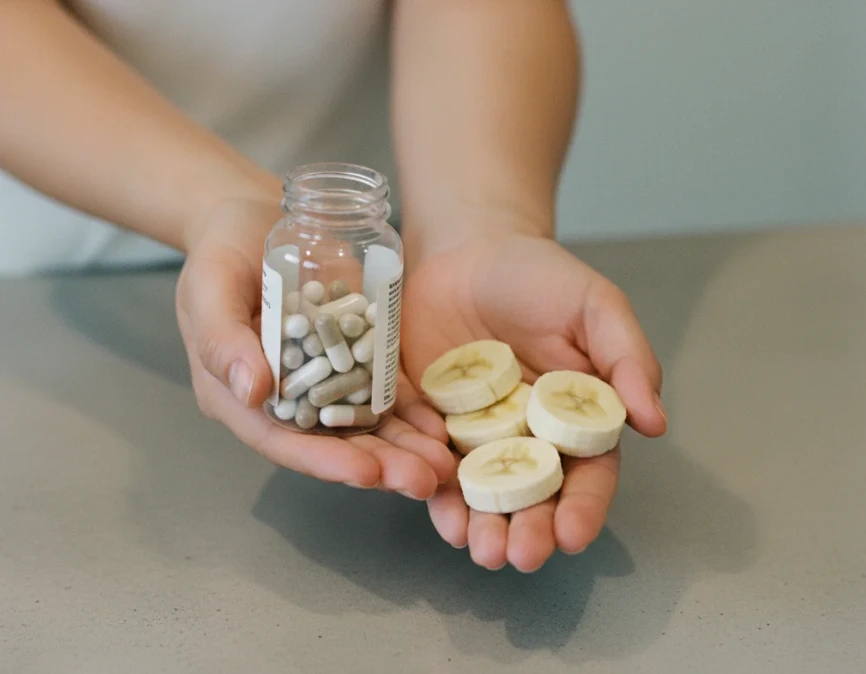 유산균 캡슐과 바나나를 함께 들고 있는 손 이미지